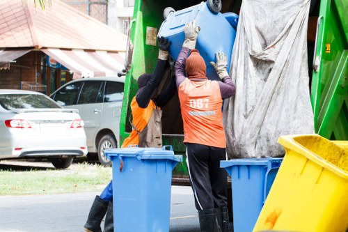 Workers sorting materials beside a skip